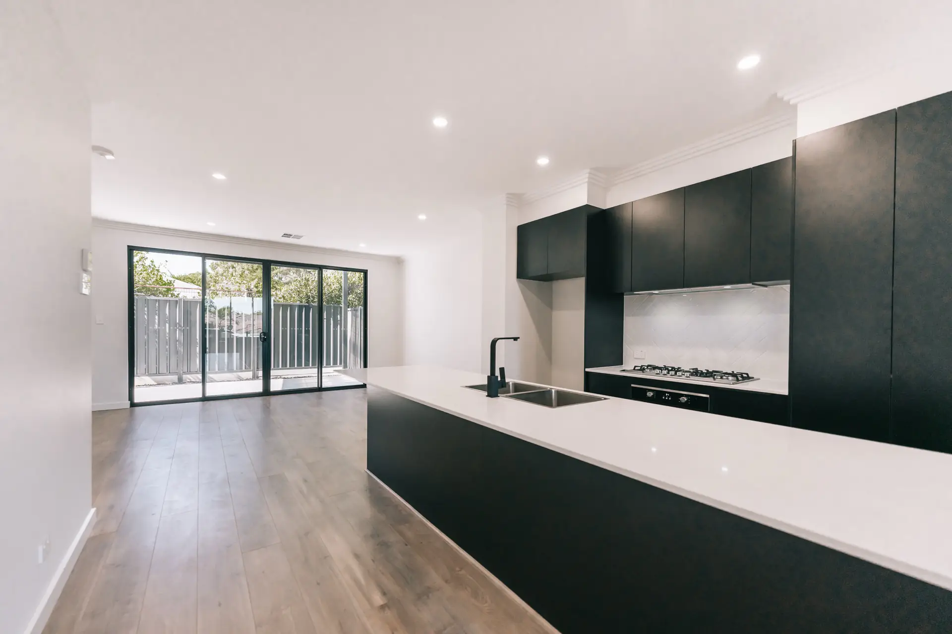 Kitchen island with black cabinetry and white benchtop.
