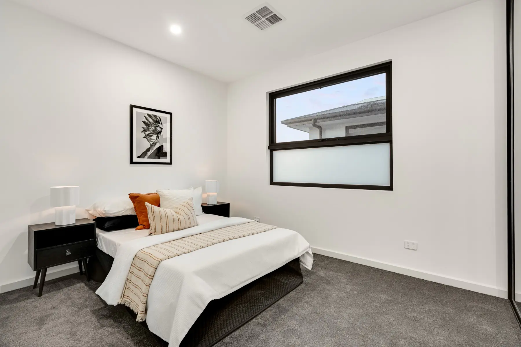 Bedroom with neutral styling and black framed window.