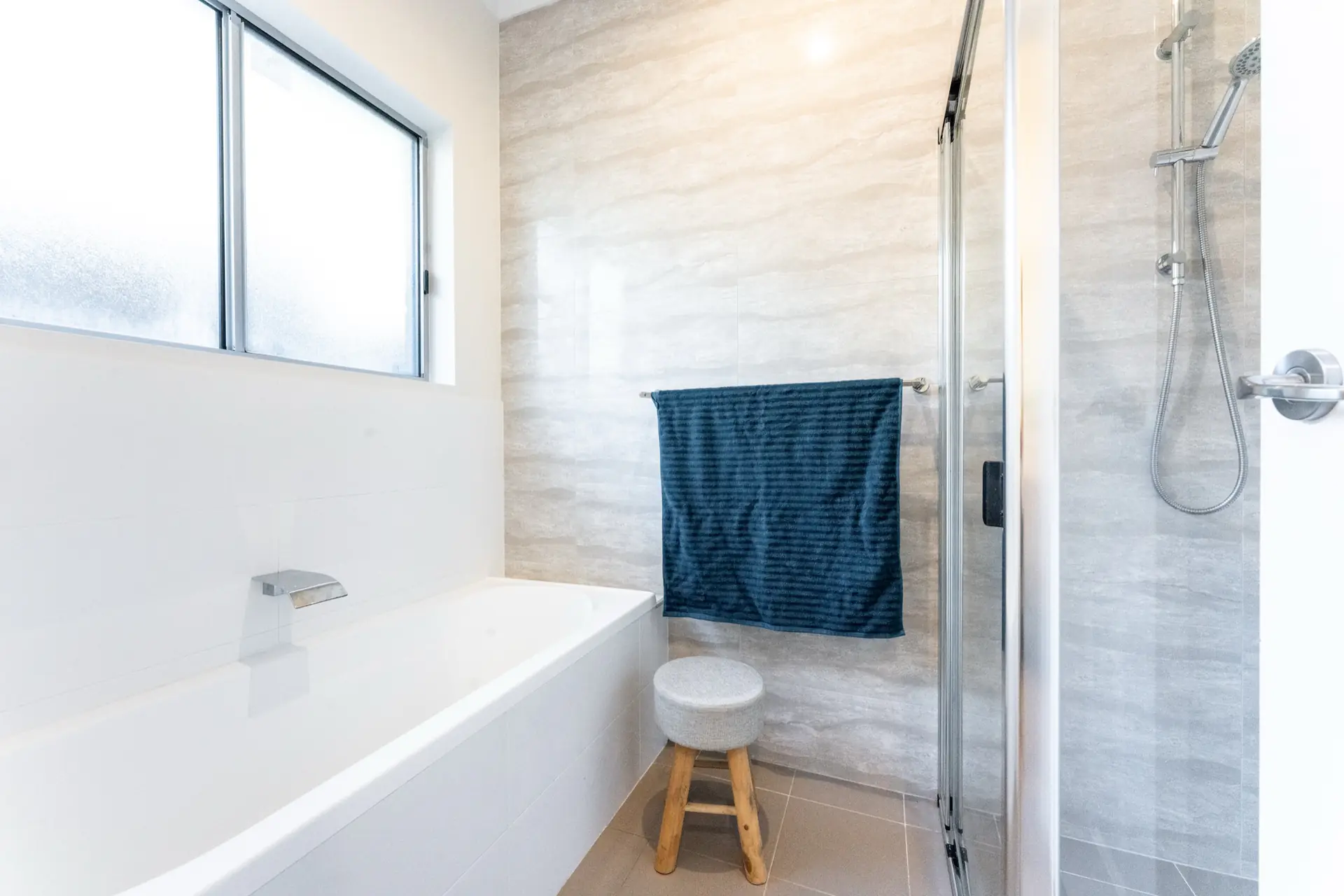 Bathroom with bath, shower and pale wall tile.