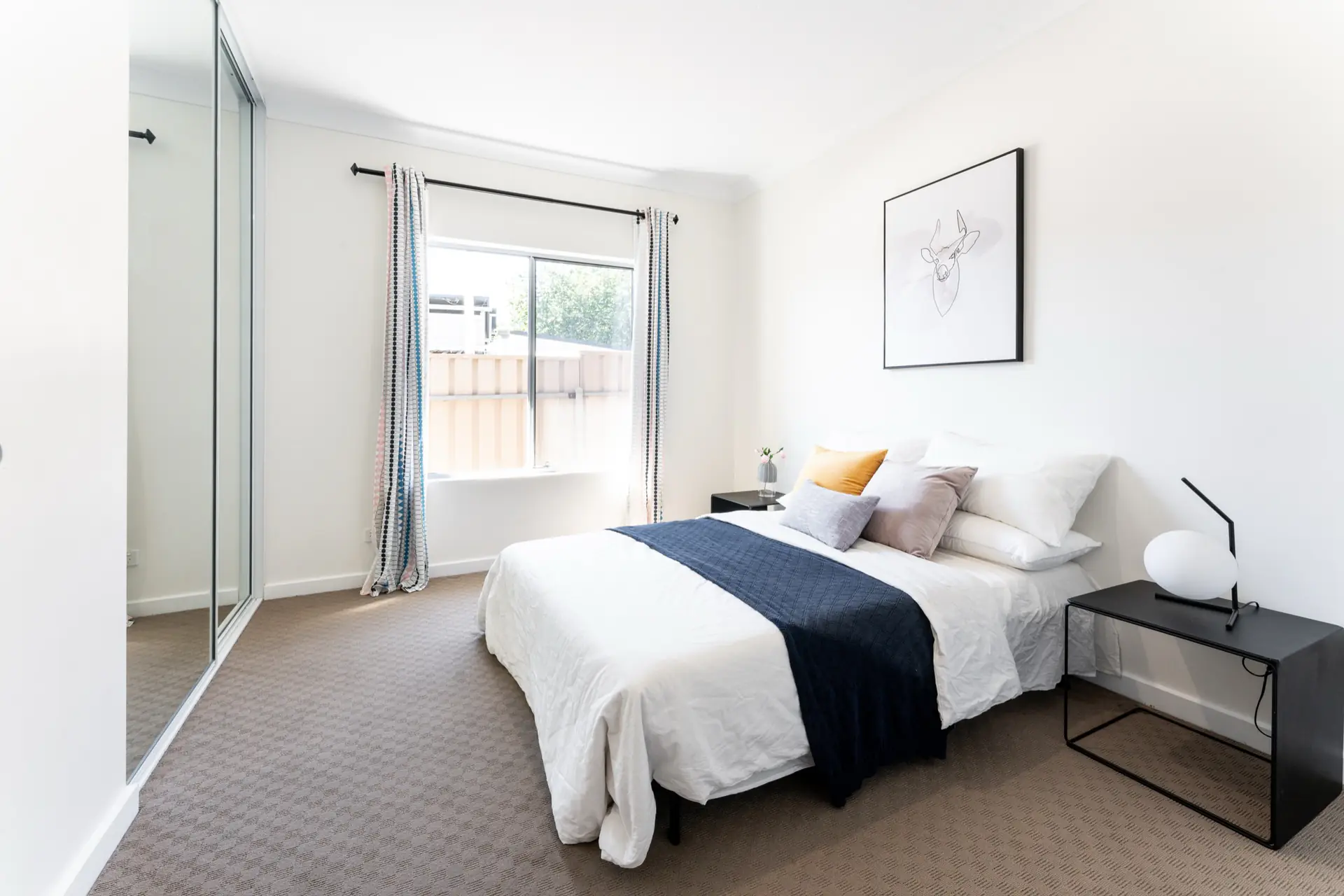 Bedroom with mirrored robe, white bedding and navy throw.