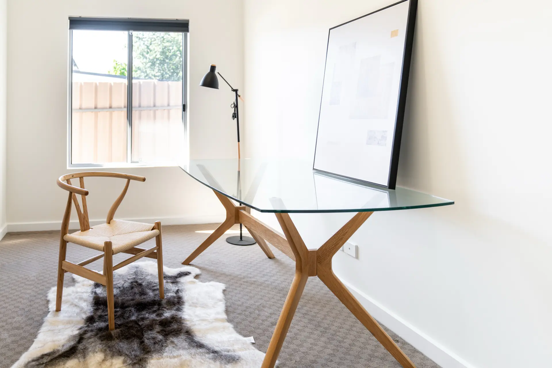 Study with glass desk, timber chair and soft daylight.